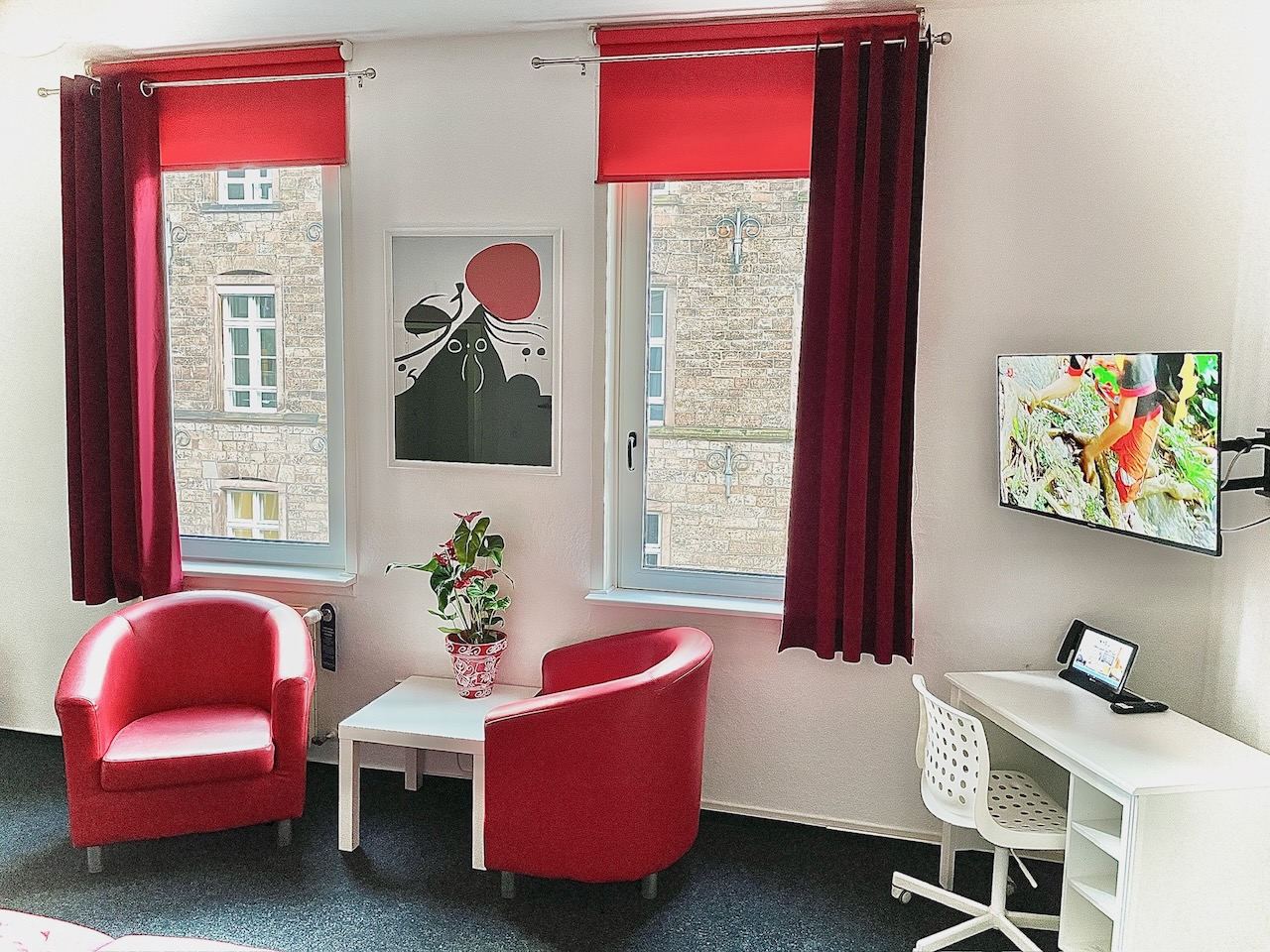 Dreibettzimmer mit zwei roten Sesseln vor den Fenstern