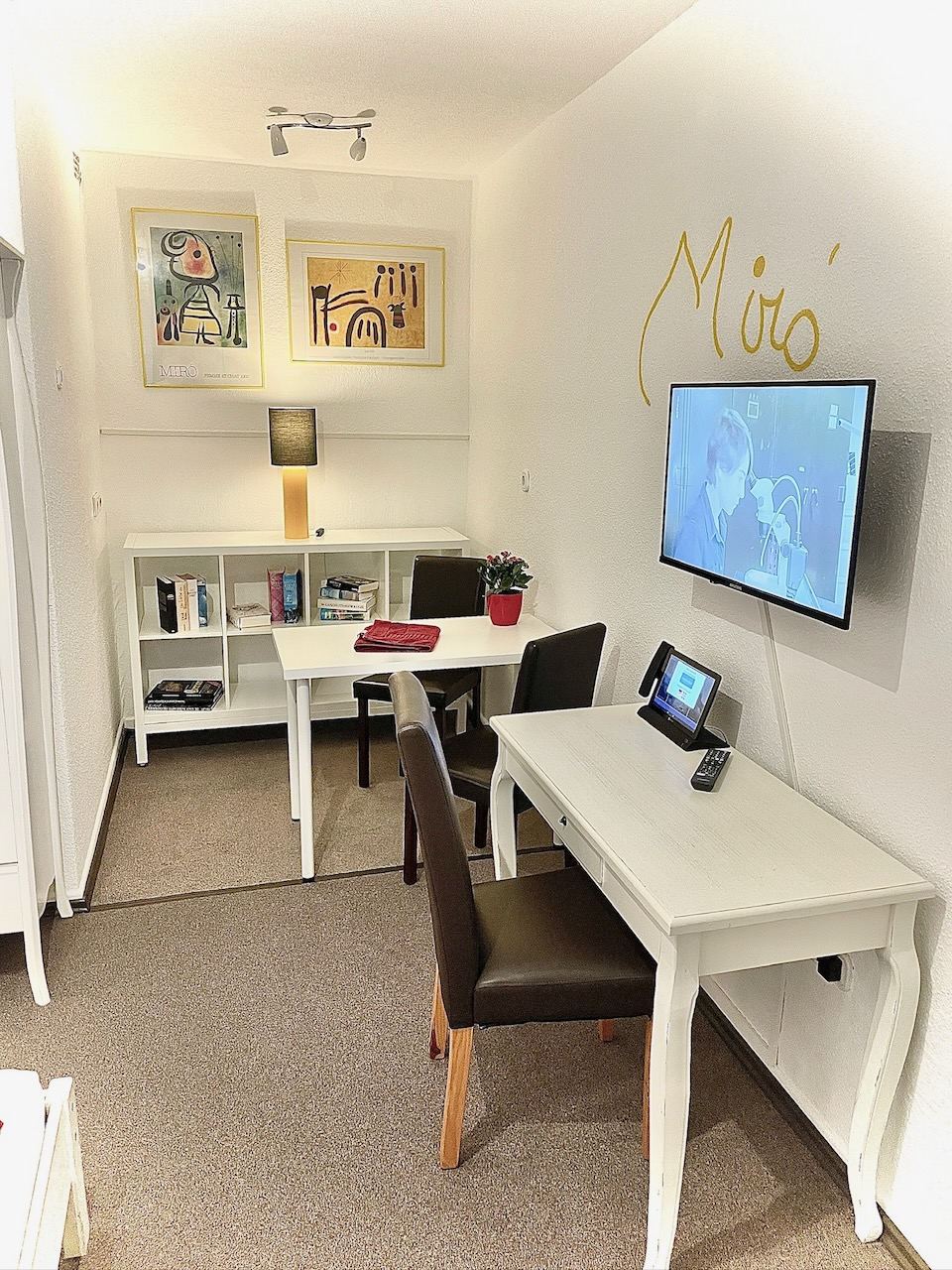 Arbeitsplatz mit zwei Tischen, Bücherregal und Flachbild-TV