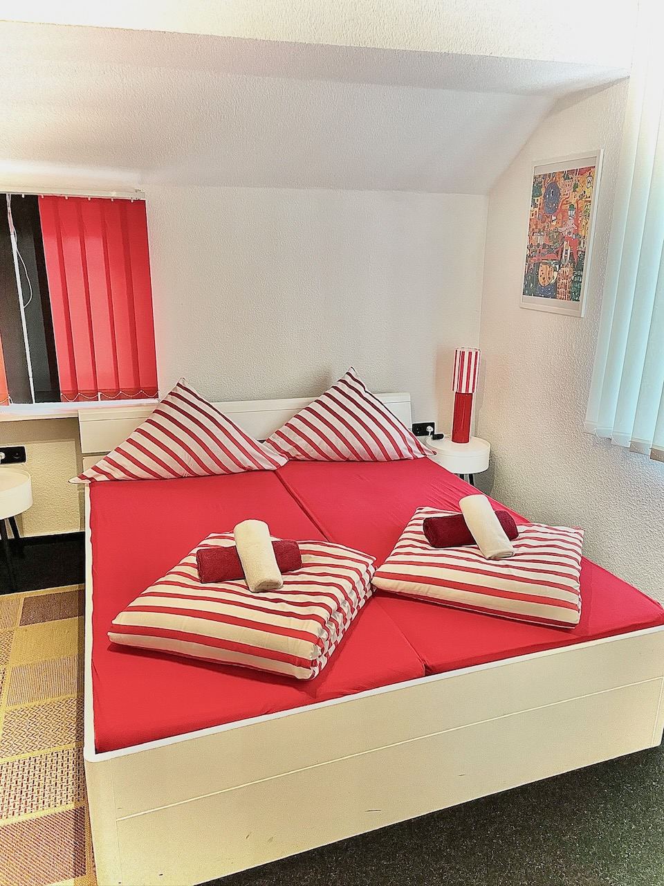 Doppelzimmer mit grau gemusterter Bettwäsche und Teppich