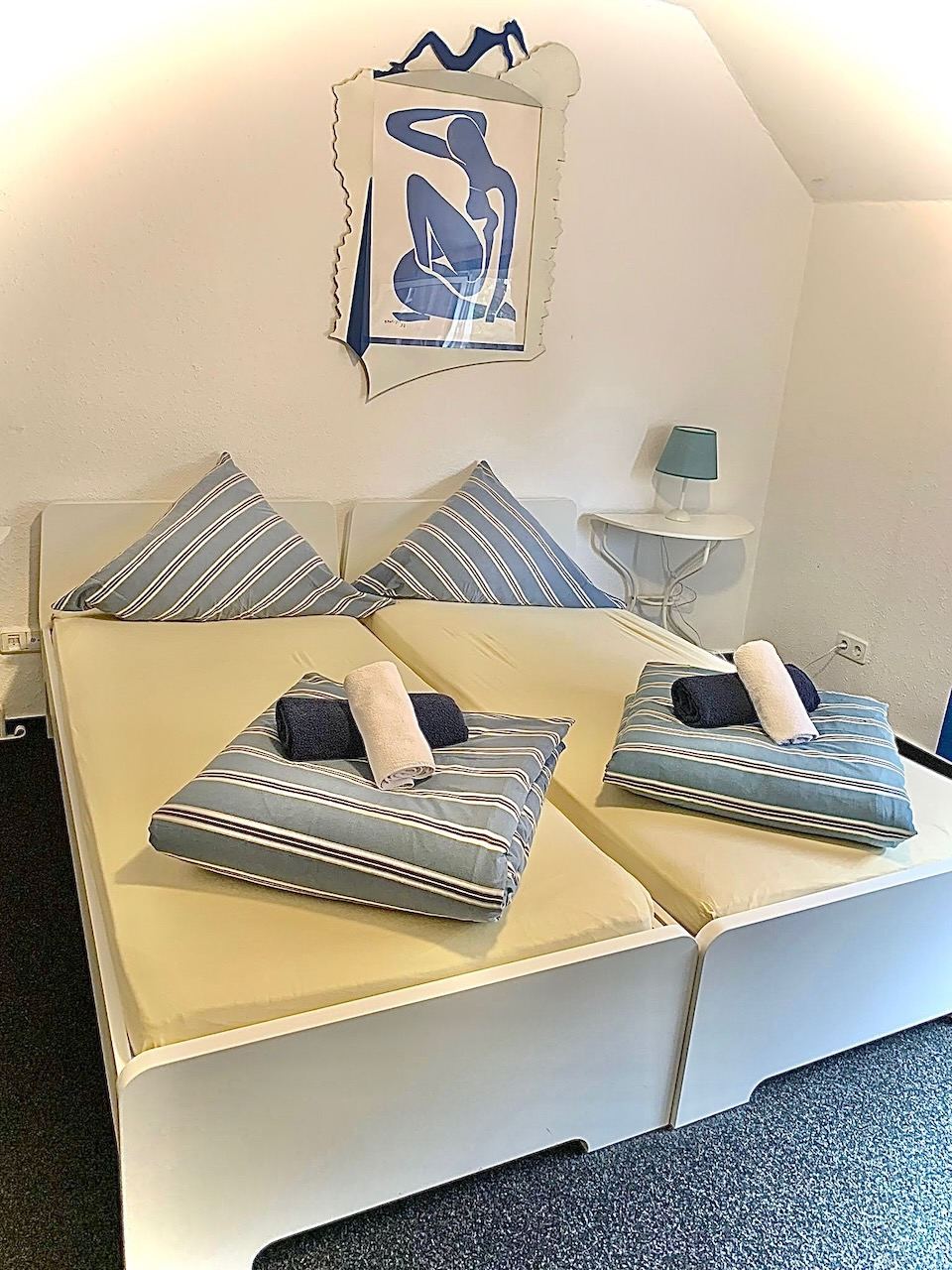 Doppelzimmer mit blau gestreifter Bettwäsche unter der Dachschräge