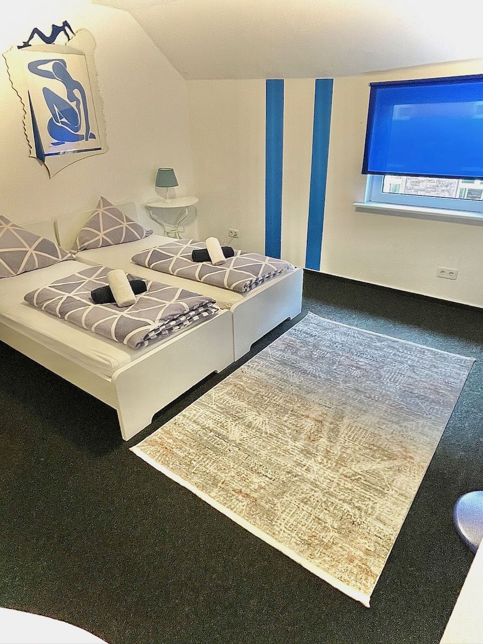 Doppelzimmer mit rot-weiß gestreifter Bettwäsche unter der Dachschräge