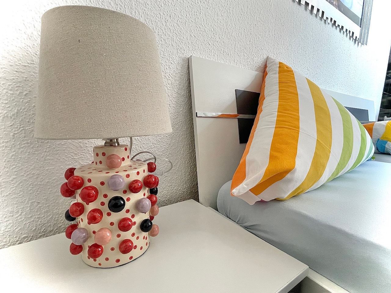 Nachttisch mit gepunkteter Lampe neben dem Bett