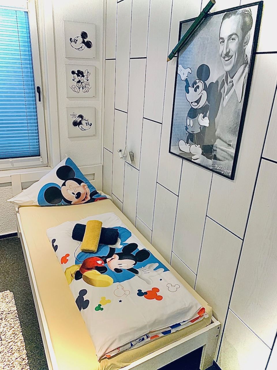 Einzelzimmer mit Micky-Maus-Bettwäsche und gerahmten Grafiken